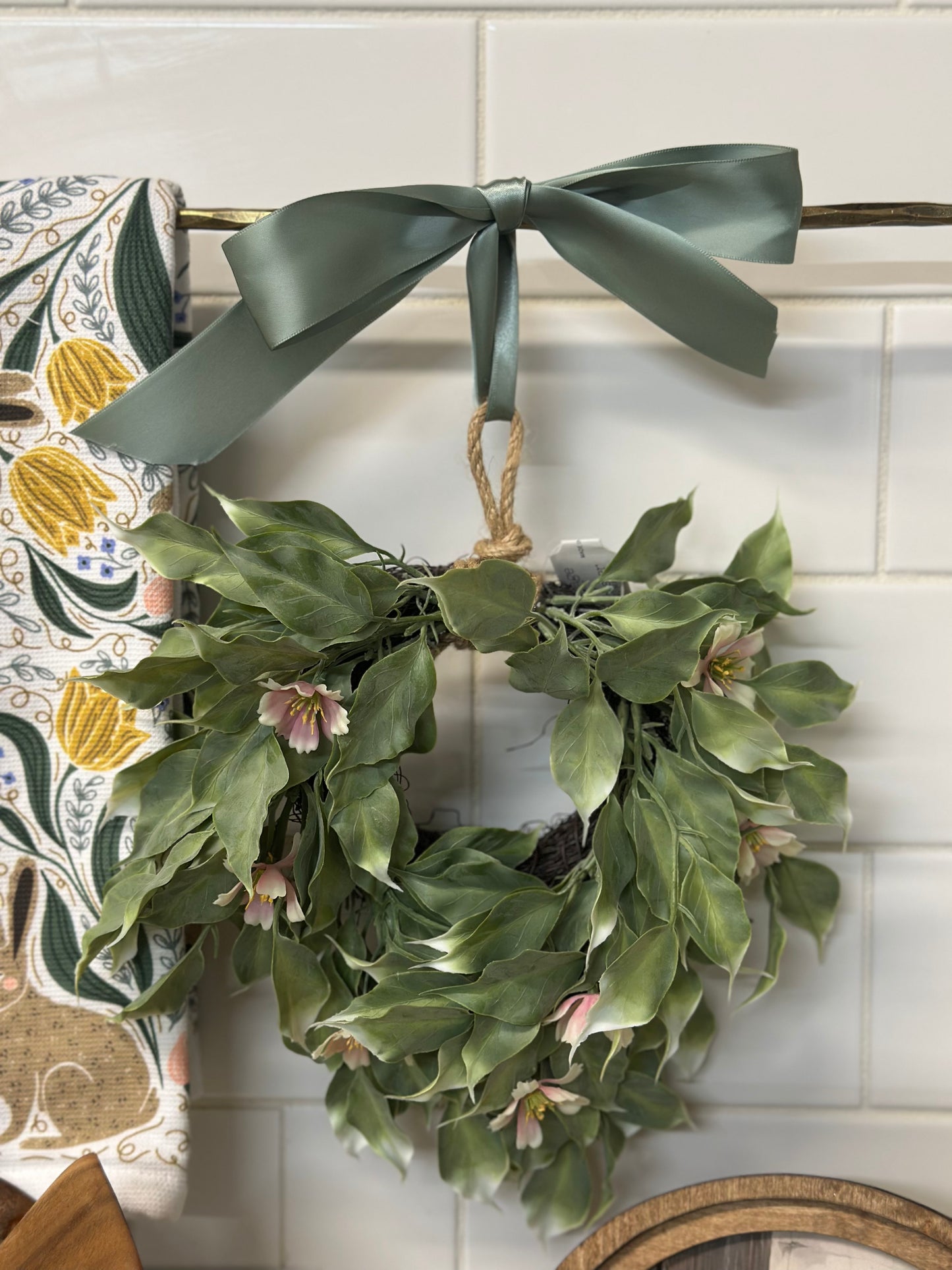 Green wreath with a hanging on a tiled wall