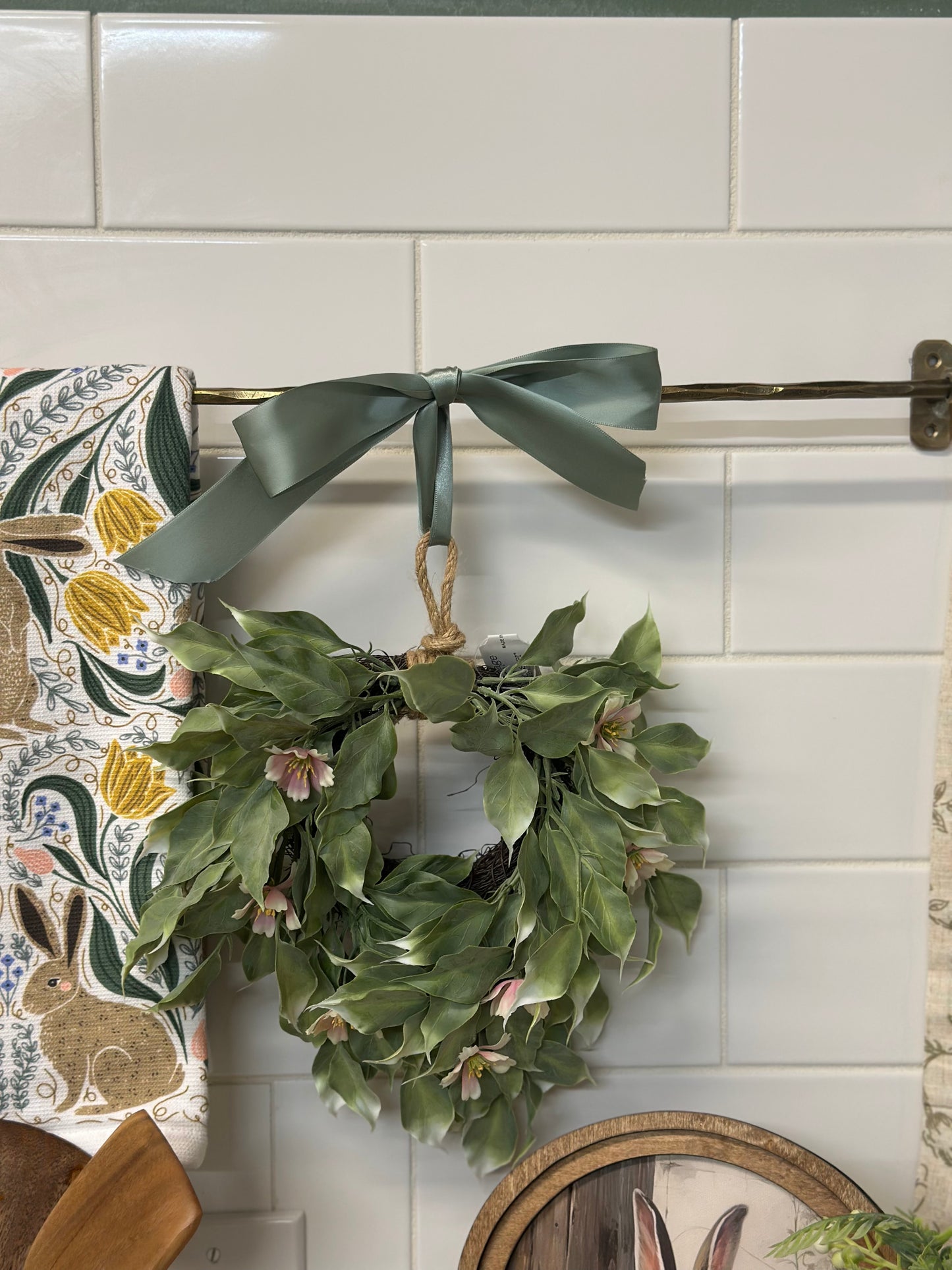 Green wreath with a bow hanging on a tiled wall